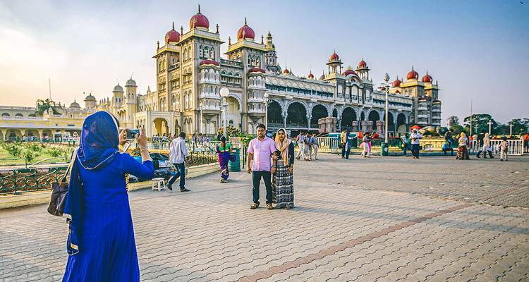 Des touristes prenant des photos devant le palais de Mysore.