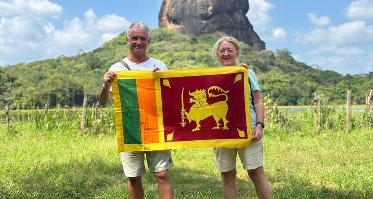 Pareja sosteniendo la bandera de Sri Lanka con la Roca de Sigiriya al fondo.