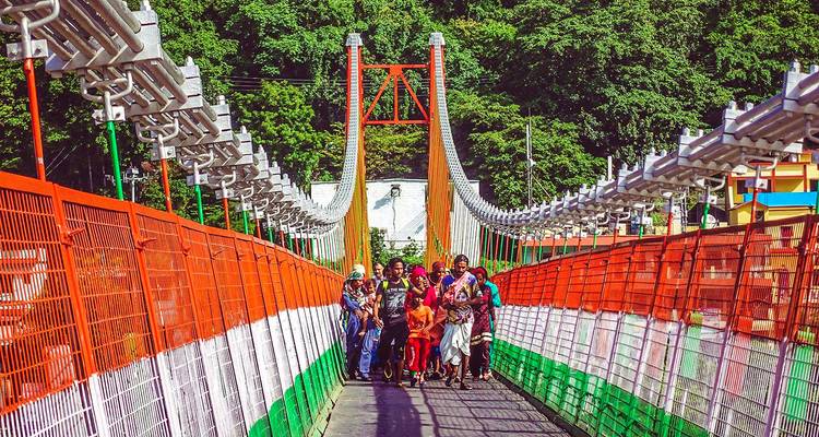 Eine Hängebrücke mit gehenden Menschen, geschmückt mit Farben, die der indischen Flagge ähneln.