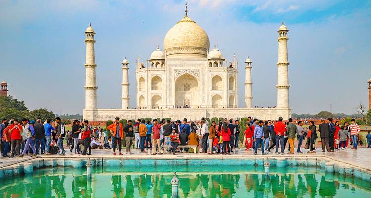 Le Taj Mahal avec de nombreux touristes et un reflet dans un bassin.