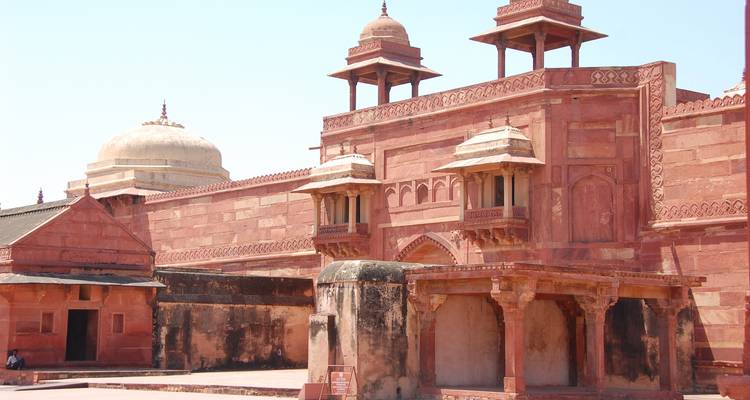 Bezoekers in Fatehpur Sikri met rode zandstenen gebouwen.