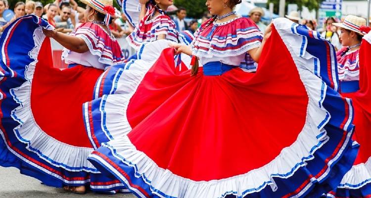 Traditionele dansers die rode, witte en blauwe jurken dragen in een parade.