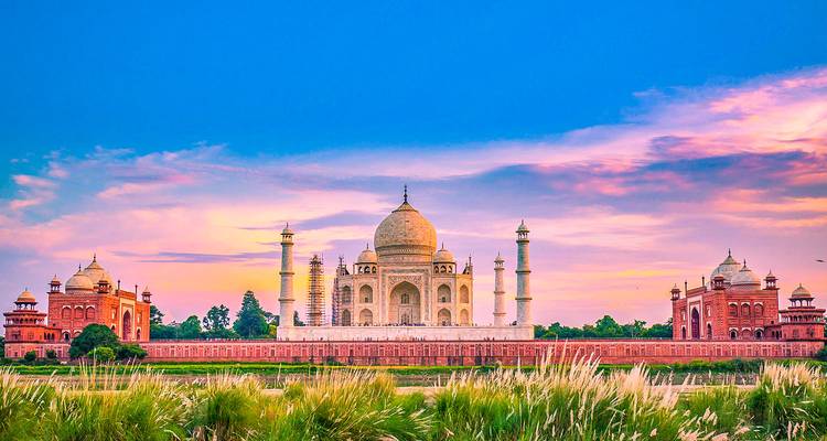 El Taj Mahal rodeado de hierba exuberante y un cielo colorido.