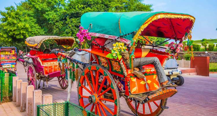 Colorful horse-drawn carriages decorated with flowers on a street.