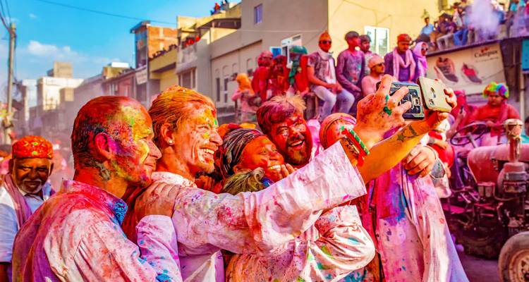 Group of people enjoying a colorful festival, taking selfies.