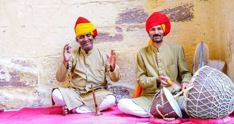 Two musicians in traditional attire sitting with instruments.