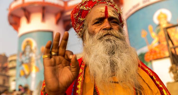 Close-up van een glimlachende man in traditionele kleding met tempelachtergrond.