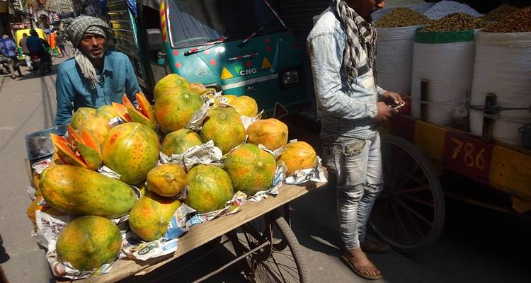 Straatverkoper die papaja's verkoopt vanaf een karretje in een drukke marktstraat.