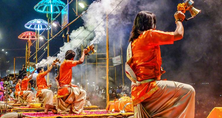 Devotos realizando aarti en la orilla del río durante el festival nocturno.