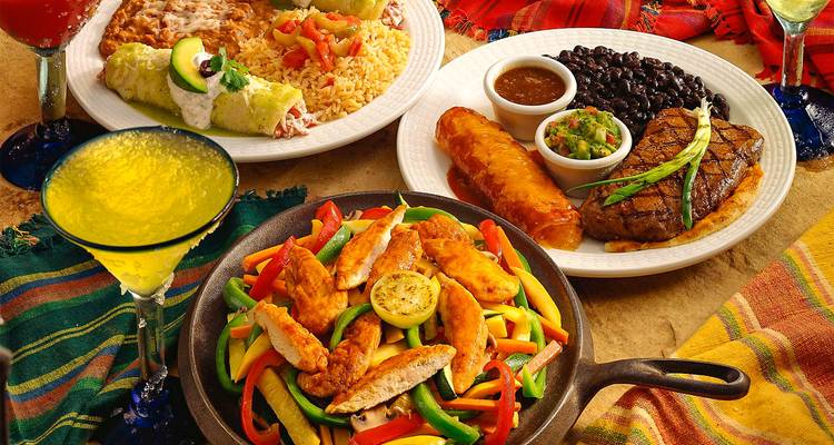 Surtido de platos de comida incluyendo fajitas, frijoles y un bistec.