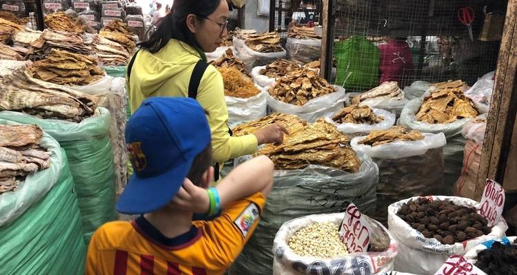 Escena de mercado con personas examinando productos secos en bolsas grandes.