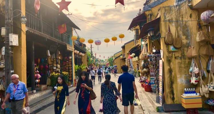 Mercado callejero bullicioso con gente caminando, faroles vibrantes y tiendas a ambos lados.
