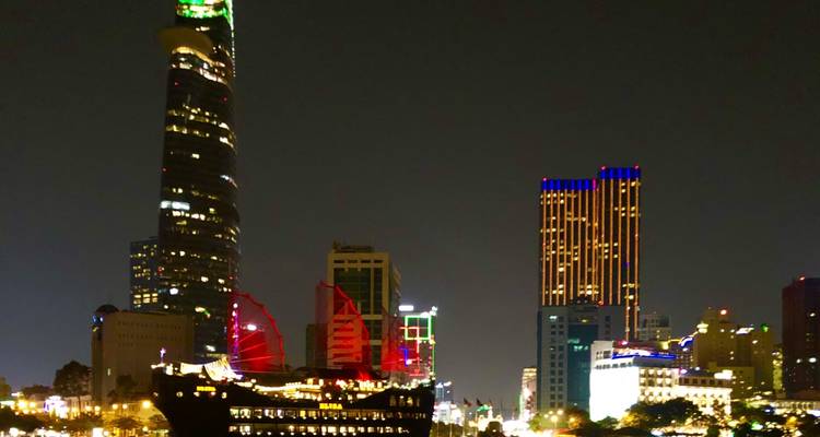 Paisaje urbano moderno iluminado con un barco prominente en el agua.