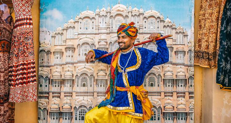 Man in traditional attire with Hawa Mahal backdrop.