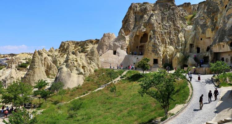 Toeristen die wandelen in een rotsachtig landschap met grotten.