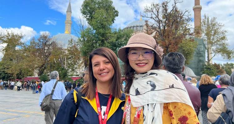 Two women smiling in front of historical architecture.