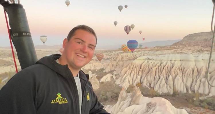 Man in front of a view with hot air balloons.