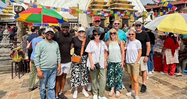 Groupe de touristes devant un stupa avec des parapluies colorés.