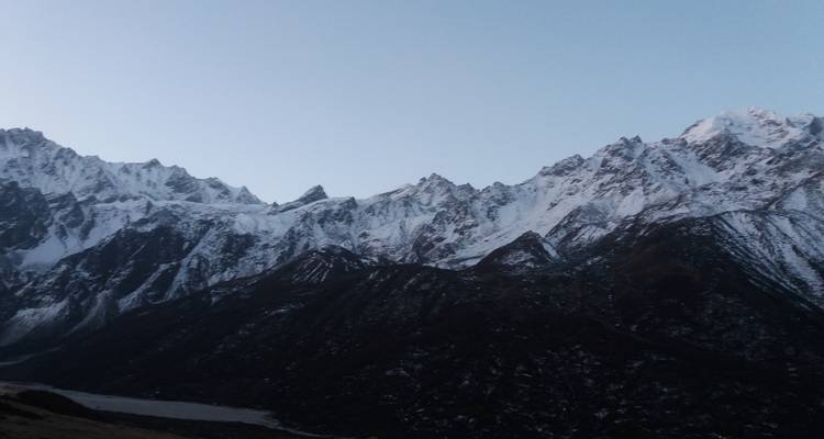 Schneebedeckte Berge mit dunklen Tälern unter einem klaren Himmel.