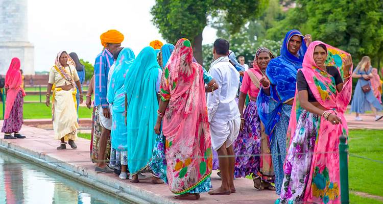 Personas en saris coloridos cerca de un sendero con vegetación.