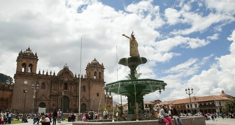 A fountain in front of a colonial-style building in a square.