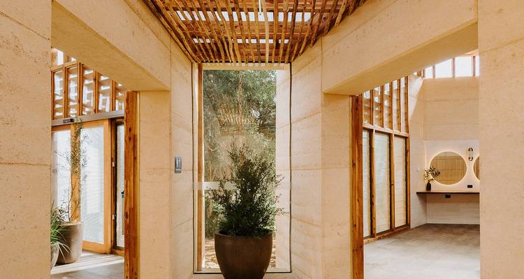 Interior de spa minimalista con muros de tierra apisonada, listones de madera y luz natural.