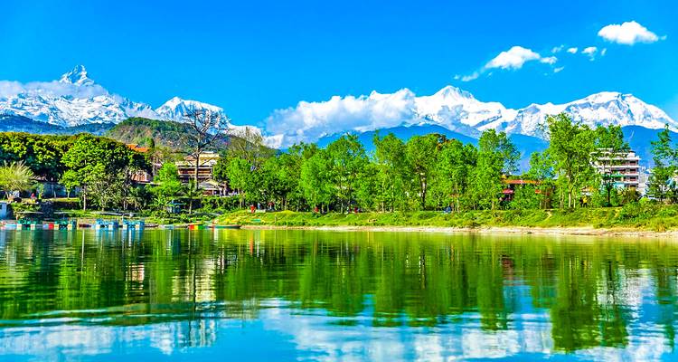 Lac reflétant les arbres et les montagnes sous un ciel bleu dégagé.