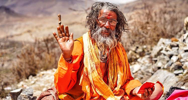 Saint homme en tenue traditionnelle saluant avec la main levée.