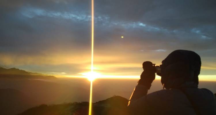 Silhouette of a person photographing a sunset.