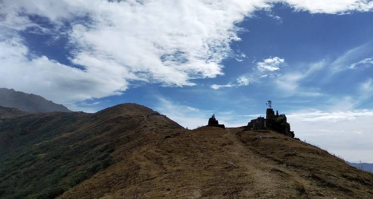 Open hillside under a blue sky with small structures.