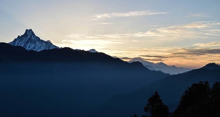 Hazy sky with silhouetted mountain peaks at dawn.