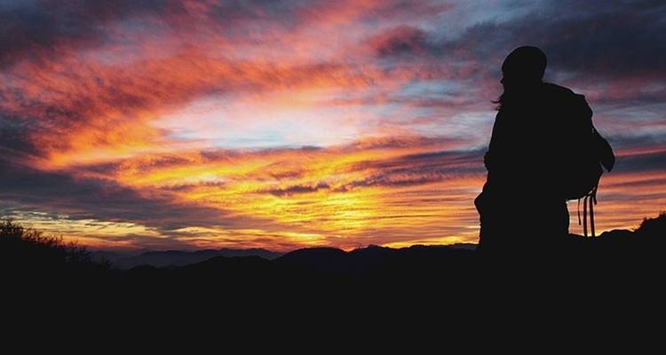 Silhouette of person against a colorful sunset sky.