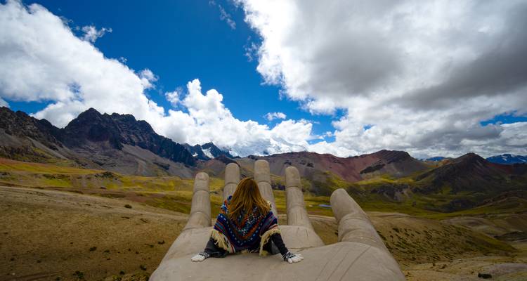 Individual relaxing on an oversized stone sculpture with mountain vistas.