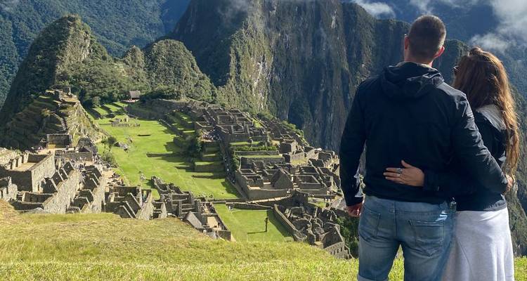 Stel staat arm in arm en bewondert de iconische ruïnes van Machu Picchu hoog gelegen in de Andes.