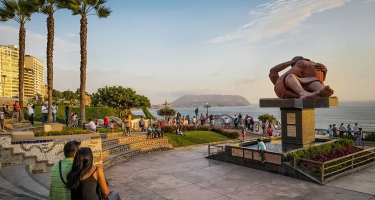 Seaside park with a sculpture and people walking.