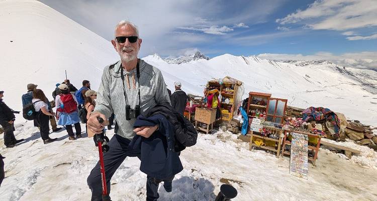 Una persona de pie en un terreno cubierto de nieve con gente y puestos de mercado.