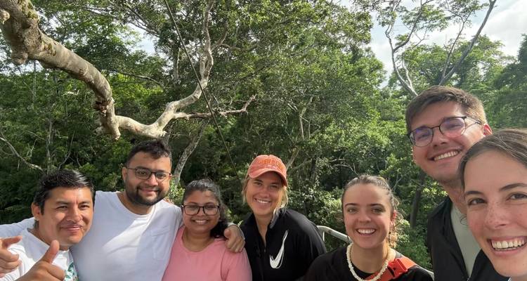 Selfie grupal de viajeros sonrientes en una pasarela elevada rodeada por el dosel denso de la selva tropical