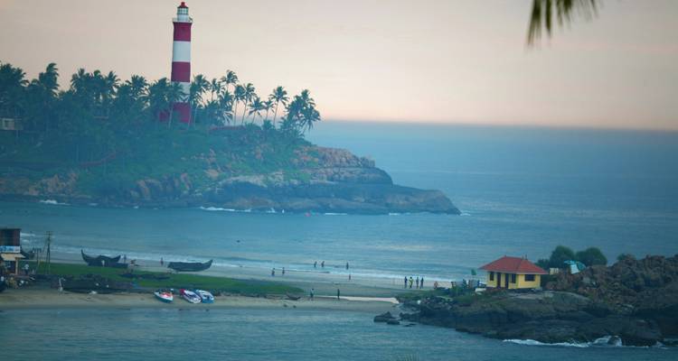 Leuchtturm mit umliegendem Strand und Blick auf entfernte Hügel.