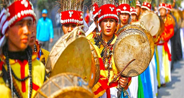 Eine Gruppe von Menschen in bunter traditioneller Kleidung, die Trommeln spielt.