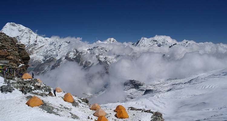 Tents in a snowy campsite with mountains in the background.