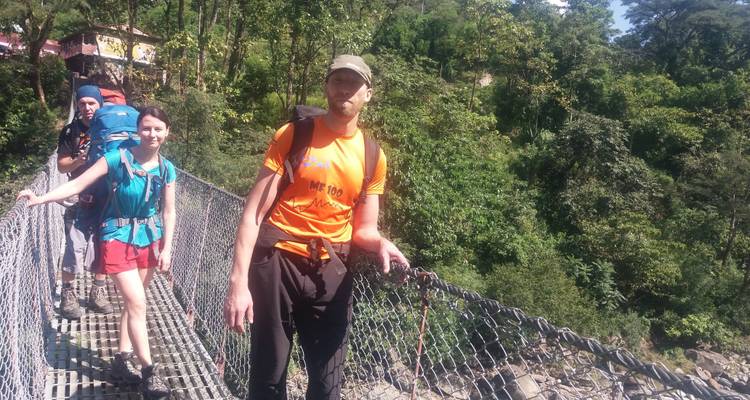 Gruppe von Wanderern, die auf einer Hängebrücke in einem Wald posieren.