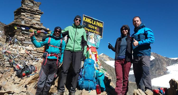 Gruppe von Wanderern, die am Kang La Pass mit Bergen im Hintergrund posieren.