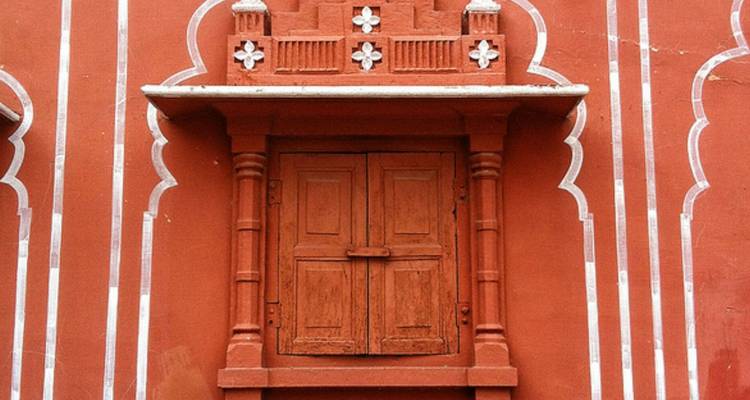 Ein dekoratives Fenster an einer gemusterten Wand.