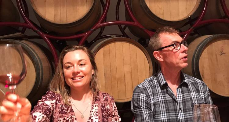 Mensen die voor wijnvaten zitten, glimlachend.