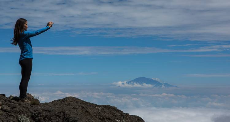 Person, die ein Foto an einem Bergaussichtspunkt macht.