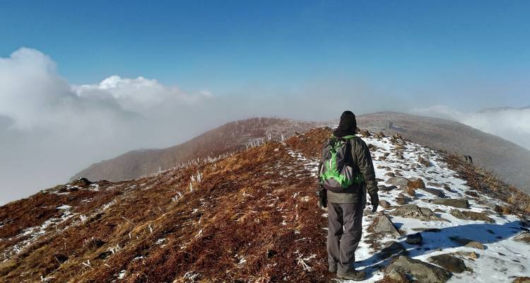 Hiker walking along a snowy ridge.