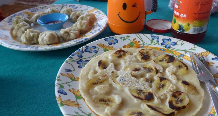 Plate of banana pancakes and momos on a table.