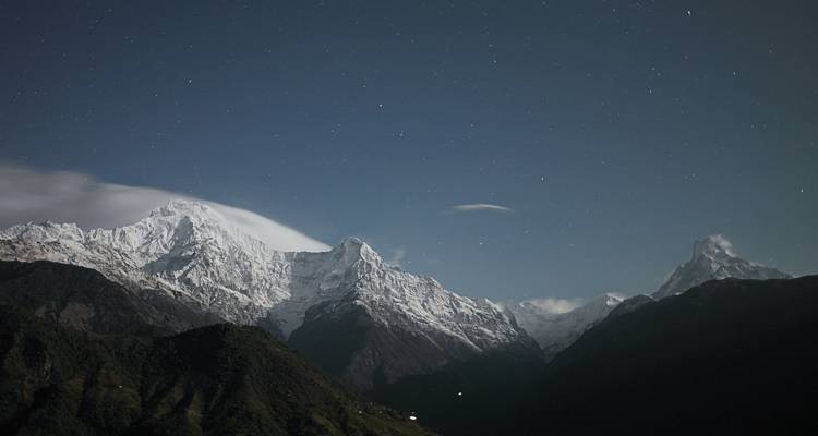Snow-capped mountains under a starry night sky.