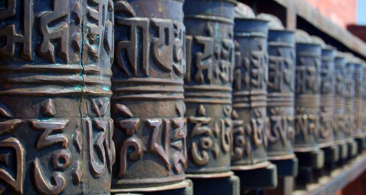 Prayer wheels with intricate carvings in a row.
