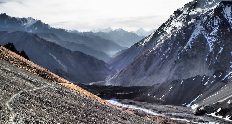 Mountainous landscape with snow and a winding path.